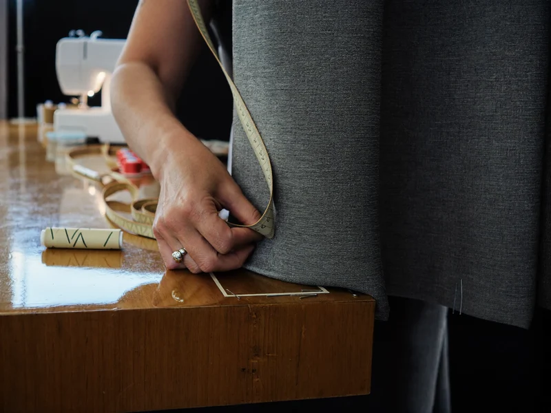 Mâini care măsoară și fixează tiv de perdea într-un atelier de croitorie
